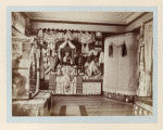 A bedspread towels, a picture of peasant girl in a frame, and curtains