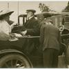 Unidentified man and woman sitting opposite one another in a motorcar.