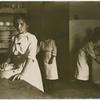 Kitchen scene. Young woman in the foreground.