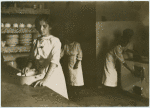 Kitchen scene. Young woman in the foreground.