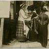 Women reading a newspaper on a street corner.