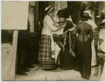 Women reading a newspaper on a street corner.