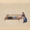 Man is bound to low platform on which a piece of wood secures his head.