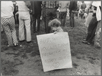 Child holding poster "But would you want your daughter to marry one?"