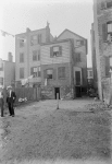 Tenement backyard with laundry & two men in suits