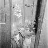 Toilet with newspaper on seat and pipes bound in rags