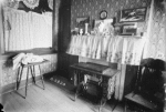 Inhabited parlor with sewing machine and cluttered shelf