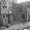 Backyard with outhouses, laundry, tricycle, mother with child