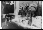 Inhabited parlor with sewing machine and cluttered shelf