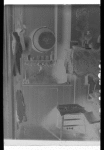Interior of room: chair, shelf with comb, brush, lamp, bottles, clothing