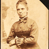 Studio portrait of unidentified woman, arms on back of chair.