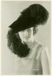 Woman modeling elaborate feathered hat.