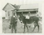 Man with mule in front of farmhouse