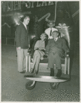 Amusements - Performers and Personalities - Barbara Bennett and man riding in American Express push chair