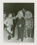 Amusements - Shows and Attractions - Wild West - Indian man putting headdress on Grover Whalen