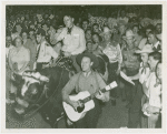 Amusements - Shows and Attractions - Wild West - Man riding bull while other man plays guitar