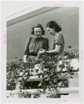 Fairgrounds - Landscaping - Women with plants on balcony of Electrified Farmhouse