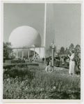 Fairgrounds - Visitors - Two women taking photographs in grass in front of Trylon and Perisphere