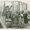 Federal Housing Administration - Houses - Construction - Man and two women looking at plans in front of frame of house