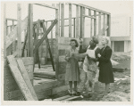 Federal Housing Administration - Houses - Construction - Man and two women looking at plans in front of frame of house