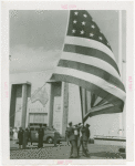 Flags - Men pulling down American flag outside of Australian Pavilion