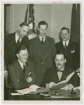 German Consul General, Johannes Borchers, signing contract with Grover Whalen while officials look on