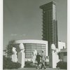 Glass Center - Man and woman walking through Baboon Fountain toward building
