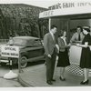 Information Booths - Attendant helping man and woman at booth shaped like Perisphere outside of Holland Tunnel