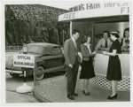 Information Booths - Attendant helping man and woman at booth shaped like Perisphere outside of Holland Tunnel