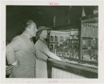 Grover Whalen and Anna Neagle inspecting dollhouse