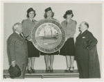 New England Participation - Harvey Gibson and man looking at giant seal of New Hampshire held by Fair guides