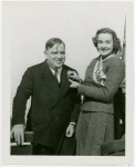 New York World's Fair - Employees - Bakers - Woman pins Fiorello LaGuardia with pin denoting him dunking expert
