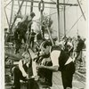 Petroleum - Geologists confer with foreman of oil drilling crew, framework in background