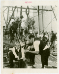 Petroleum - Geologists confer with foreman of oil drilling crew, framework in background