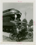 Railroads on Parade - Woman standing on train and man and woman on horseless carriage