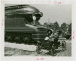 Railroads on Parade - Woman standing on train and man and woman on horseless carriage