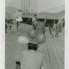Sports - Archery - Man aiming bow at balloons tired to other man's hat