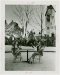 Sports - Ice Skating - Man on ice skates jumping over two chorus girls sitting at table
