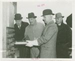 Theme Center - Trylon and Perisphere - Construction - Edward Stettinius, Jr. (U.S. Secretary of State) driving rivet into Perisphere while Grover Whalen and others look on