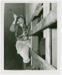 Theme Center - Trylon and Perisphere - Construction - Worker in harness nailing plywood onto Trylon