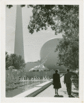 Theme Center - Trylon and Perisphere - View of Trylon and Perisphere with sculpture, fountains, man and woman in foreground