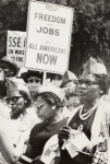 Women with sign "Freedom and Jobs for All Americans Now"