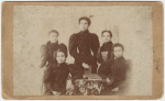 Five women, two sitting, three standing, around a table with books