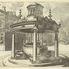 Double pulley well in plaza with fountain in background