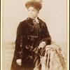 Studio portrait of woman wearing hat, and velvet coat.