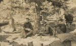 Frederick V. Field and two others eating a picnic meal in the woods with a horse in the background