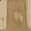 Man in light colored coat in front of tapestry