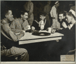 Service men at Stage Door Canteen (New York City) seated at table drinking and talking.