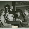 Mr. Cecil B. DeMille serving coffee to service men seated with hostesses
