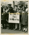 Mixed race group of children carrying sign: "No Child is Free Until ALL are Free," circa early 1960s